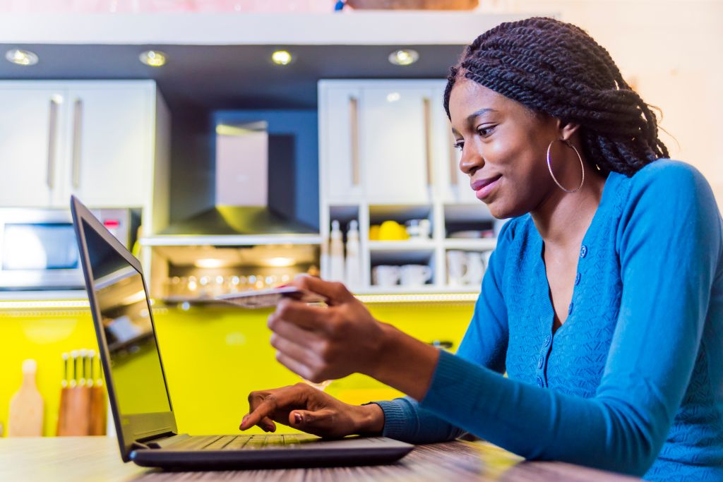 Smiling black woman online shopping using computer and credit card