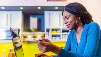 Smiling black woman online shopping using computer and credit card