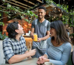 Waiter serving drinks to a couple at a cafe