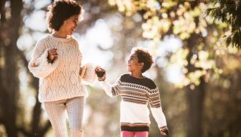 Carefree African American mother and daughter running in autumn day.