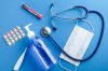 Medical disposable mask, thermometer, hand sanitizer, stethoscope, tablets, blood in a test Tube on a Blue Background.