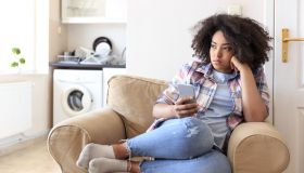 Young woman sitting at home and using smart phone