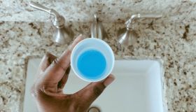 Woman Holds Cup of Mouthwash