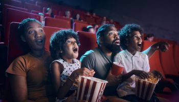 Shocked black family watching a movie in theatre.