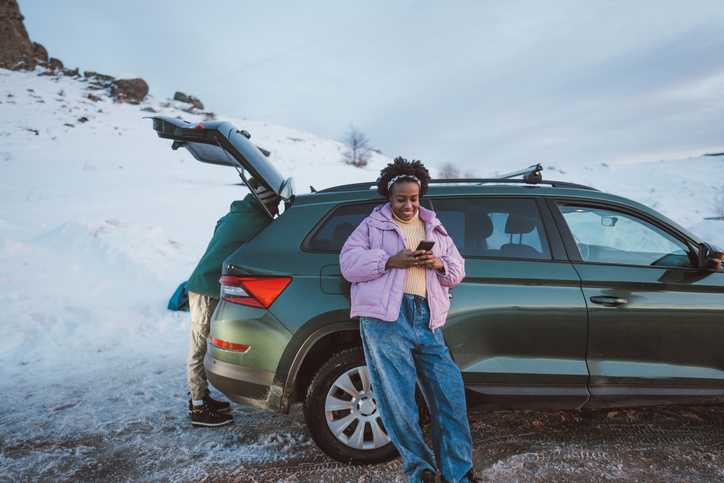 Young woman using mobile phone while on a road trip